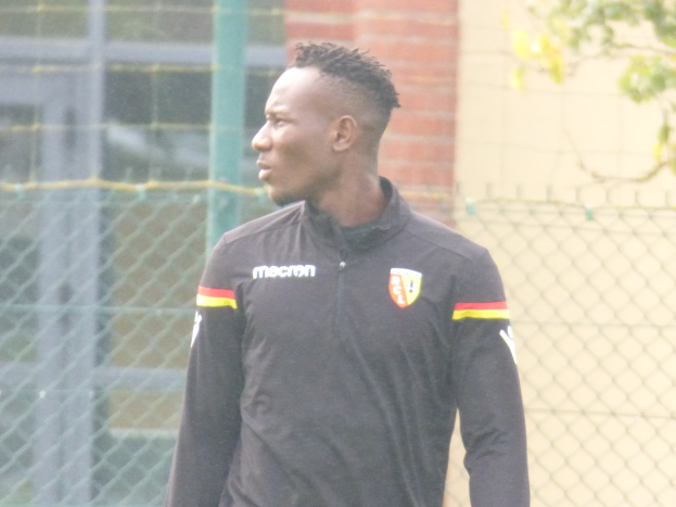 Ein Mann In Einer Schwarzen Jacke Steht Auf Einem Fußballfeld, Umgeben Von Einem Zaun Und Einem Baum, Und Sieht konzentriert Aus During A Training Session.