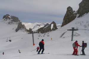 Leute in Pullovern fahren auf dem Eis Ski, mit einer Seilbahn, Bergen und einem bewölkten Himmel im Hintergrund.