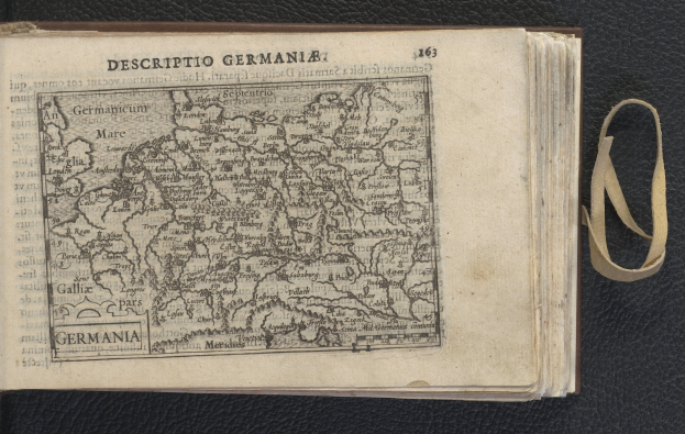 Offenes Buch auf einer schwarzen Oberfläche mit einer historischen Deutschlandkarte daneben.