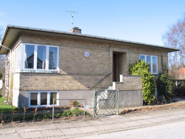 Zweizimmer-Detached-Bungalow zum Verkauf in St Johns Wood, Swindon, mit Dach, Fenstern, Tür, Treppe, Metallzaun, Pflanzen, Gras, Bäumen, Satellitenschößel und wolkenverhangenem Himmel.