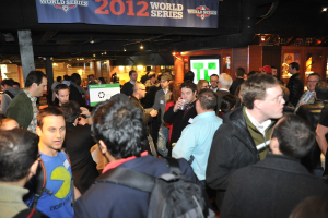 Eine große Menschenmenge versammelte sich bei einem Event mit einem Bildschirm, der ein Bild anzeigt, Lichtern und einer Holzwand im Hintergrund.