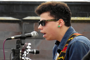 Eine Person steht vor mehreren Mikrofonen mit einer Wand dahinter.