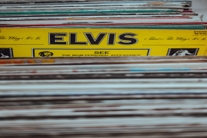 Ein ordentlicher Stapel Elvis Presley-Platten auf einem Tisch, mit sichtbaren Titeln und einem unscharfen Hintergrund.