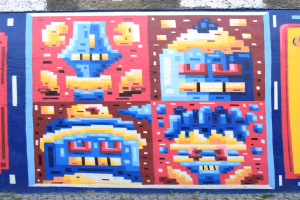 Ein buntes Wandgemälde an der Seite eines Gebäudes in Berlin, Deutschland, das verschiedene Formen und leuchtende Farben zeigt.