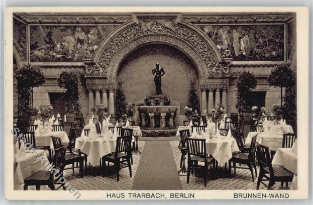 Schwarzes und weißes Foto eines alten Berliner Restaurant-Interieurs mit Tischen, Stühlen, Blumenvasen, einer Statue im Hintergrund, Wandskulpturen, Pflanzen und Text unten.