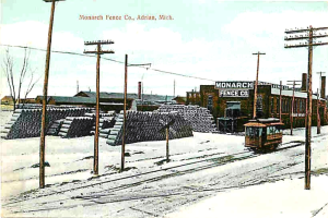 Eine schneebedeckte Landschaft mit einem Fahrzeug auf einer Bahn, umgeben von Pfosten, mit einer Sammlung von Gegenständen hinter den Pfosten und einem Fabrikgebäude im Vordergrund.