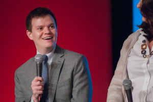 Ein Mann hält ein Mikrofon in der Hand und lächelt, eine Frau steht neben ihm und hält ebenfalls ein Mikrofon