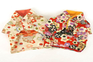 Ein weißer Boden mit einem orangefarbenen Blumenkleid links und einem roten Kleid mit weißen und violetten Blumen rechts.