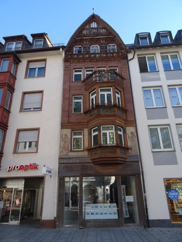 Gewerbliches Immobilienangebot in Heidelberg, Deutschland, mit einem Gebäude mit vielen Fenstern an einer Straße unter einem klaren blauen Himmel.