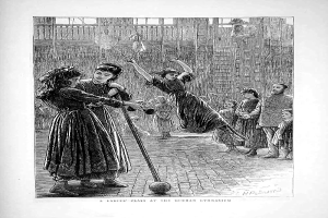 Eine Schwarzweiß-Radierung von Kindern, die mit einem Ball in einer Turnhalle spielen, mit zwei Mädchen in der Mitte, die Stöcke halten, und einem Text unten, der "Eine Damenklasse im Deutschen Turnverein" lautet.