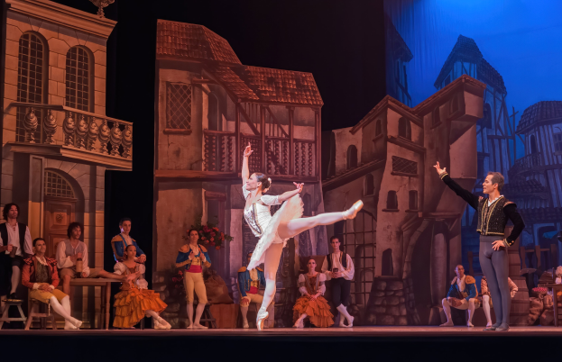 Zwei Tänzer performen auf einer Bühne im Royal Opera House in London, mit einem Publikum im Vordergrund, das sitzt und steht.