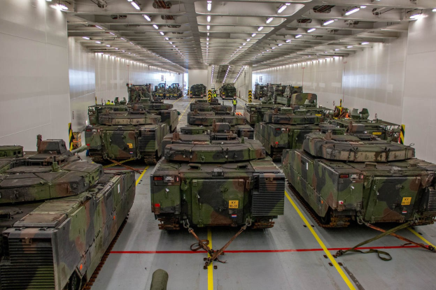 Ein grosser Militaraerhangar mit Reihen von Militaraerfahrzeugen, Wanden an beiden Seiten und Deckenleuchten.