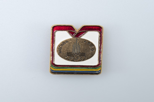 Eine weiße Fläche mit einem Abzeichen der Olympischen Winterspiele 1980 in Moskau, Russland, das ein farbenfrohes Design und die Wörter 'Olympische Spiele' zeigt.