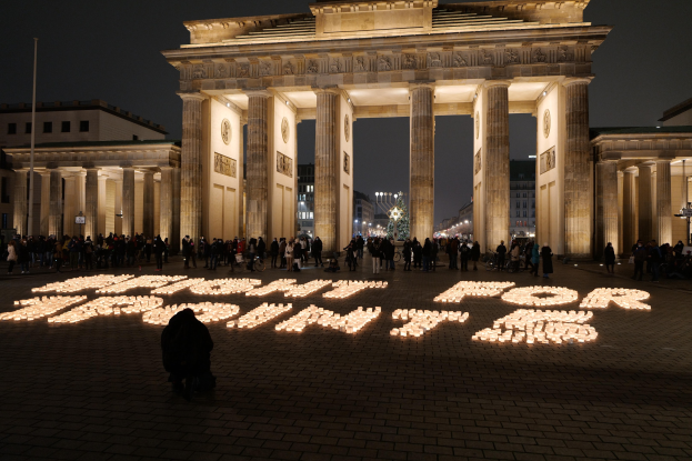 Gruppe von Menschen vor dem beleuchteten Brandenburger Tor in Berlin, Deutschland, mit "Kampf für die Freiheit" auf dem Boden im Vordergrund.