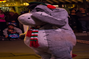 Eine Person in einem Tierkostüm steht zwischen einer Menge von Menschen, mit Licht auf dem Dach darüber.