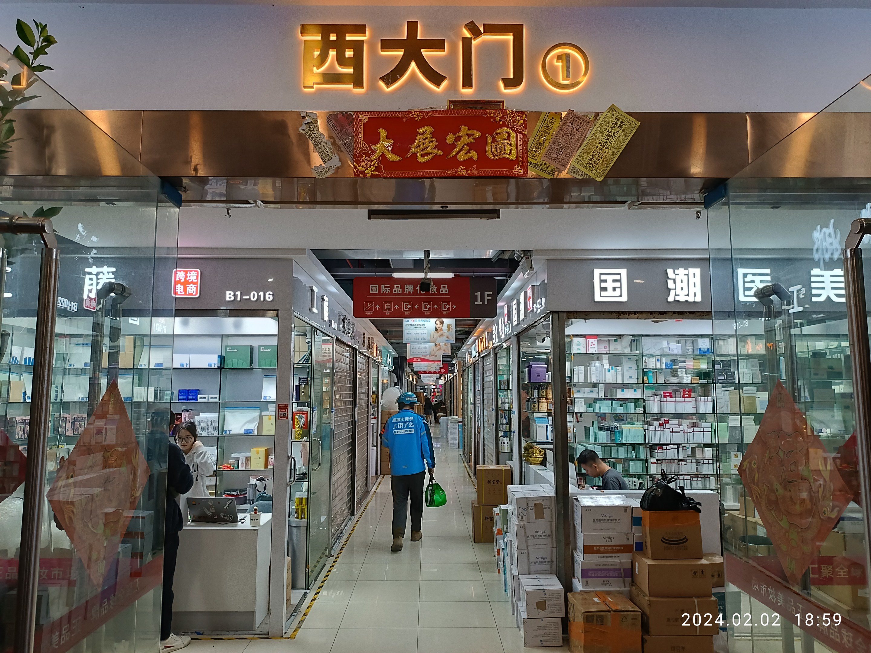 Innenansicht einer chinesischen Apotheke mit Glaswänden, Regalen voller Artikel, verstreuten Kartons, einer Pflanze links und einem Schild oben, das auf eine chinesische Drogerie hinweist.