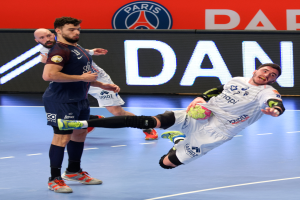 Eine Gruppe von Männern spielt Handball auf einem Platz, einer hält den Ball, im Hintergrund ein Paris Saint-Germain-Futsal-Team-Schild.