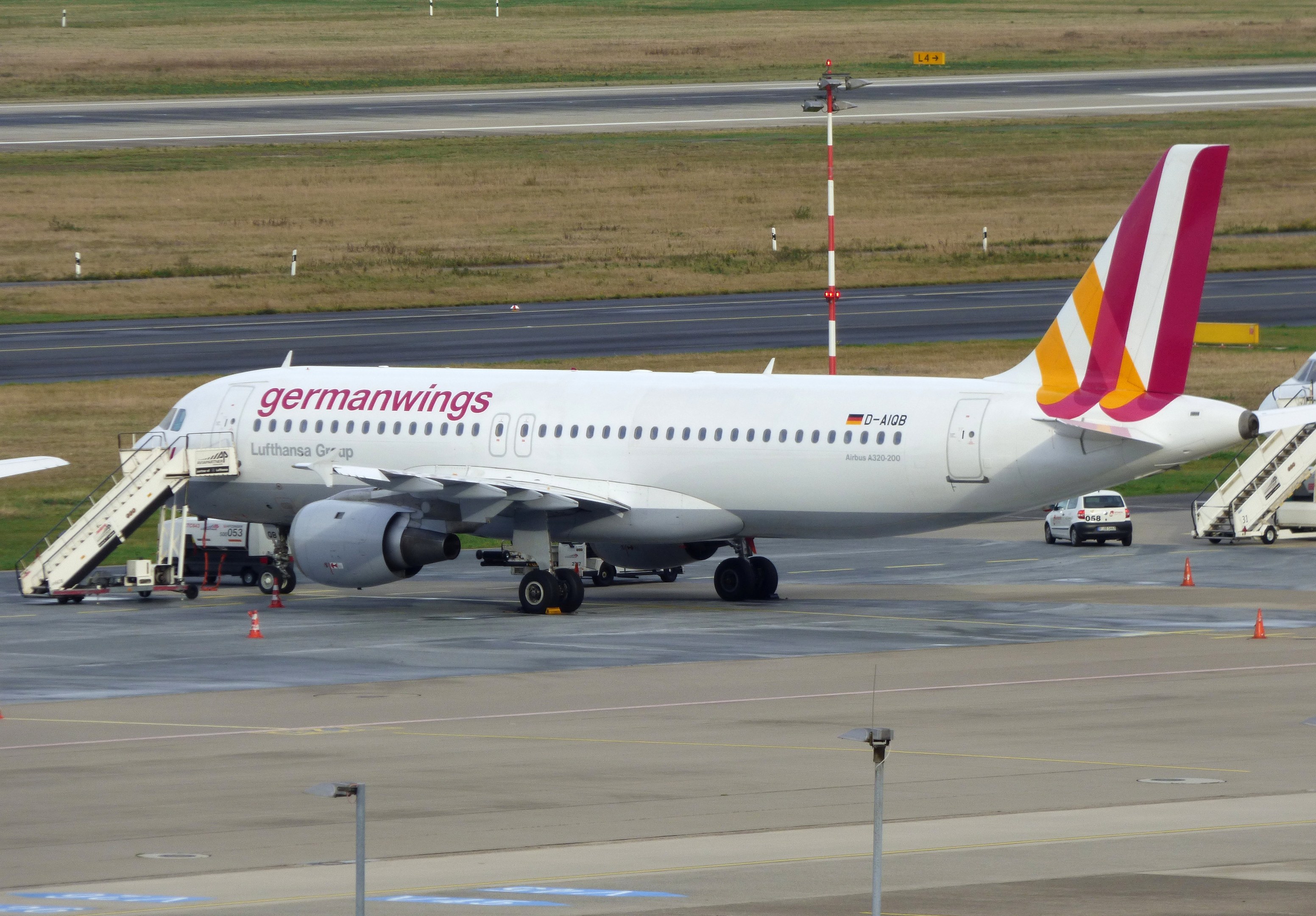 Germanwings Airbus A320-200 am Frankfurter Flughafen mit Bodenfahrzeugen, Verkehrskegeln, Pfählen und Gras im Hintergrund.