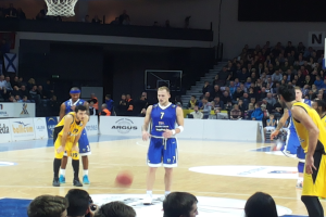 Eine Gruppe von Männern in blauen und gelben Uniformen, die Basketball auf einem Court spielen, umgeben von einer Menge auf den Tribünen, während eines 7days Eurocup Regular Season Round 2-Spiels zwischen Fenerbahçe und Real Madrid.