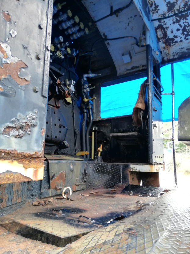 Ein rostiger und abgenutzter Truck-innenraum mit sichtbarer Rostschäden, vor Bäumen und einem klaren blauen Himmel.