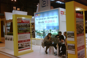 Eine Gruppe von Menschen, die in Stühlen sitzen und einem Tisch mit einem Laptop gegenübersitzen, umgeben von mehreren Flyern mit verschiedenen Werbeanzeigen.