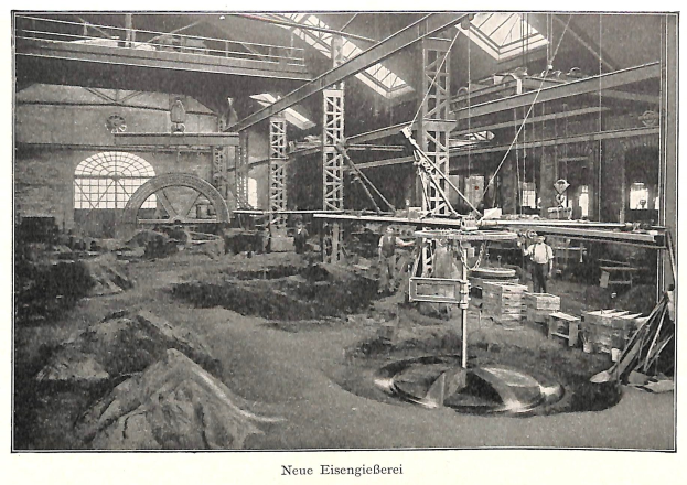 Schwarz-weißes Foto einer 19. Jahrhundert deutschen Fabrik mit Arbeitern, die an einer Maschine arbeiten, Metallstangen und Pfähle, beschriftet mit "Neue Eisenglebeerei, die erste Fabrik in Deutschland" unten.