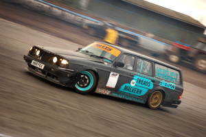 Ein Auto fährt auf einer Rennstrecke, umgeben von anderen Fahrzeugen, mit einer Person darin, der Hintergrund ist unscharf von der hohen Geschwindigkeit.