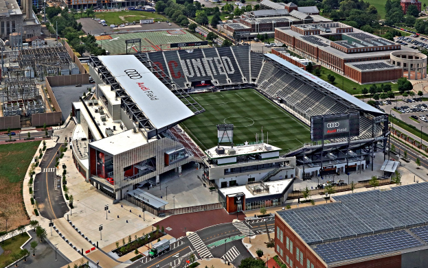 Luftbild von Audi Field, Heimat des Atlanta United Football Club, umgeben von Stadtgebäuden, Bäumen, Straßen, Fahrzeugen, Masten und Gras.